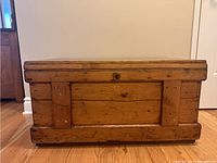 Closed view of rectangular pine blanket box showing natural wood finish, reinforced panels on front and sides.