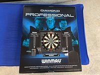 Front view of the boxed Winmau Diamond Plus Professional Darts Set showing branding and included components.