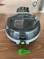 Front view of the T-Fal ActiFry Air Fryer closed, showing the locking lid with a transparent window and neon green latch button.