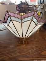 Side view of stained glass ceiling light showing white and purple glass panels with brass framing and finial base.