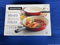 Photo of unopened box of two Tremontina enamelled cast iron skillets, 10 inch and 12 inch, showing product image and size details.