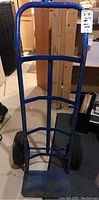 Front view of the blue metal dolly showing the frame and two tires.