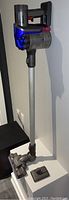 Assembled vacuum on extension wand with floor head and wall charger visible