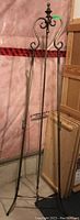 Full metal easel standing against pink insulation wall, showing full height and tripod legs.