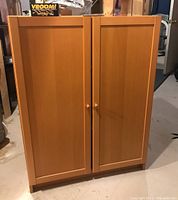 Front view of the IKEA Billy cabinet showing two paneled doors with wooden knobs, wood laminated finish