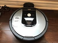 Top view of silver and black iRobot Roomba robot vacuum on hardwood floor