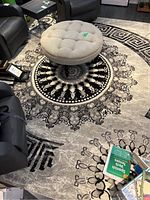 Top angle view of rug with round tufted ottoman placed centrally, showing the circular floral and geometric design