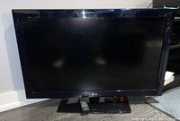 Front view of black 41 inch LG flat screen TV with remote on stand.