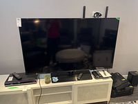 Front view of TV on pedestal stand with remote and power cable.