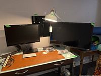 Two TVs on desk: Insignia 26" on left with detachable arm mount, Toshiba 33" to right (base not shown)