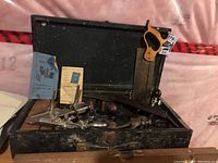 Open vintage toolbox showing various hand tools including a Record router with bits and some manuals inside the lid.