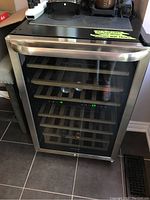 Front view of wine fridge showing glass door, wood shelves and digital display.