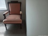 Front view of antique chair showing wood frame and pink upholstery