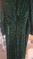 Close-up of green sequin fabric and front gathered detail of the gown.