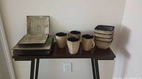 Full view of the set comprising 4 dinner plates, 4 dessert plates, 4 coffee mugs, and 4 bowls arranged on a table showing colors and patterns