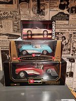 Photo showing two Burago Chevrolet Corvette model cars in original boxes, turquoise and red/white 1957 Corvette models.