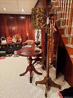 Full view of wooden coat rack with attached hooks, showing walking canes and umbrella hanging. Located near a staircase indoors on carpeted floor.