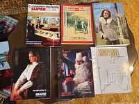 Five vintage catalogues and coffee table books displayed on a table, includes Sears, Eaton's, Simpsons, dated from 1901 to 1987.