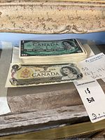 Stack of 100 Centennial Confederation one dollar notes with one darker single note on top