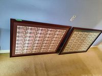 Two framed uncut bill sheets leaning against wall side by side