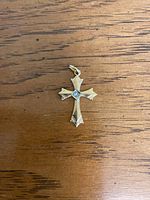 Top view of the gold cross charm showing engraved details and central stone.