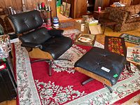 Front angle showing black leather lounge chair and ottoman on patterned rug