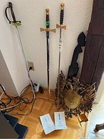 Three swords standing upright next to carved wood decor and metal crest plaque