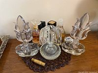 Wide view of assorted perfume bottles including large decorative glass stoppers and smaller vintage bottles on table surface.