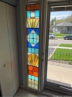 Full-height view of stained glass panel installed in doorway, showing overall design and frame.
