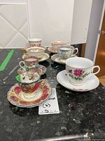 Full view of seven teacup and saucer sets arranged on countertop