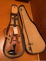Full view of violin inside open travel case with bow on lid showing overall condition