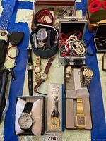 Photo of multiple watches displayed on a table, including boxed watches and assorted beads and bracelets