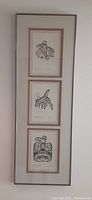 Full view of the framed set of three Bill Reid prints arranged vertically, double matted and framed, visible to wall