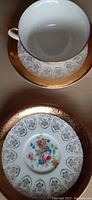 Top view of tea cup inside saucer and decorative plate showing gold trims and floral motif