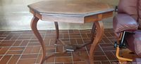 Full view of the octagonal hardwood side table showing curved legs and stretcher base