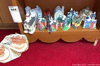 Shelf with multiple ceramic cottages and buildings displayed together showing various styles and colors