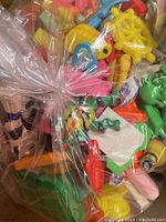 Close-up of assorted small erasers and toys in clear plastic wrap showing Disney and Cabbage Patch themed items along with colorful novelty erasers