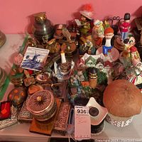 Wide view of assorted figurines, metal decorative items, and music boxes arranged on a surface showing variety and condition.