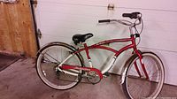 Full view of red and white Schwinn cruiser bicycle with chrome fenders and black Tim Hortons seat in a garage.