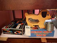 Wooden dog toy on top of an electronic musical battery operated train set box with metal slinky beside them and Melody Train box in the back