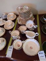 Overall view of the Aynsley set including stacked plates, teacups, saucers, creamer, and bowl arranged on a table.