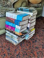 Two stacks of hard cover books on a carpeted floor next to a couch. Several volumes of The Story of Civilization series by Will and Ariel Durant visible along with other history and antiques books.