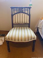 Front view of upholstered chair showing turned wood frame and striped fabric upholstery with marks