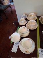 Six Coalport teacups and seven saucers displayed with floral and gold designs, minor chips visible.