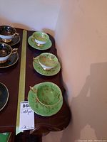 Photo of three Coalport teacup and saucer sets on a wooden table showing different designs and gold detailing