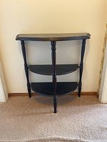 Front view of the demi-lune table showing three shelves and turned legs.
