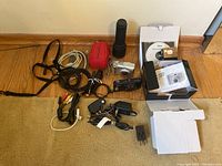 Lot contents showing Nikon Coolpix S9300 and Canon PowerShot A520 cameras and accessories including cords, cables, adapters, camera case, straps, and flashlight.