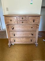 Front view of wooden dresser showing five drawers with missing hardware pulls and scratched surface.