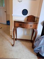Front view of wood hall table with drawer and a wood letter holder on top, showing overall design and condition.