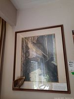 Framed print showing a detailed landscape with rocky formations and a body of water, signed by Robert Bateman.